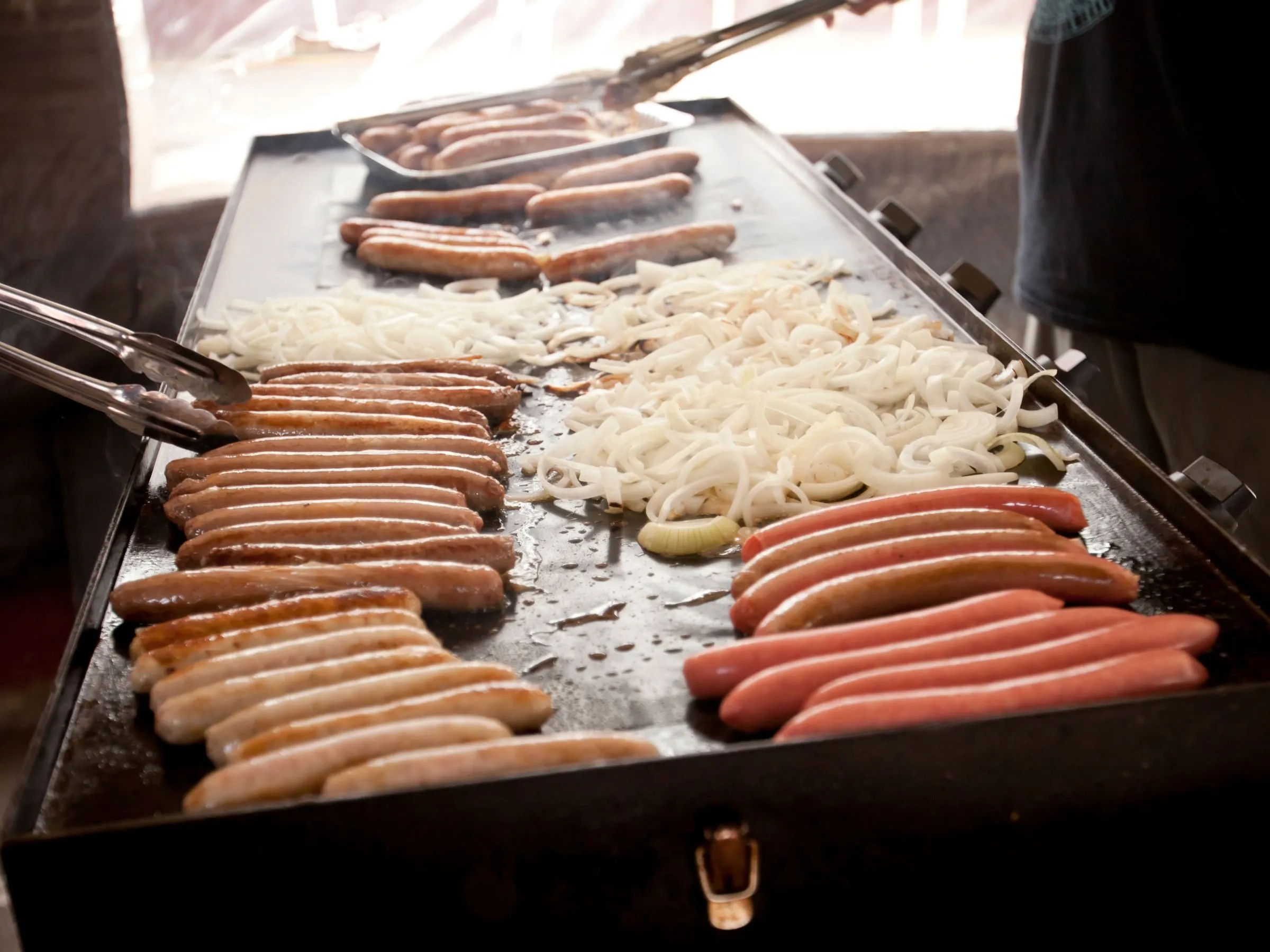 Bratwurst and sausages grilling with onions